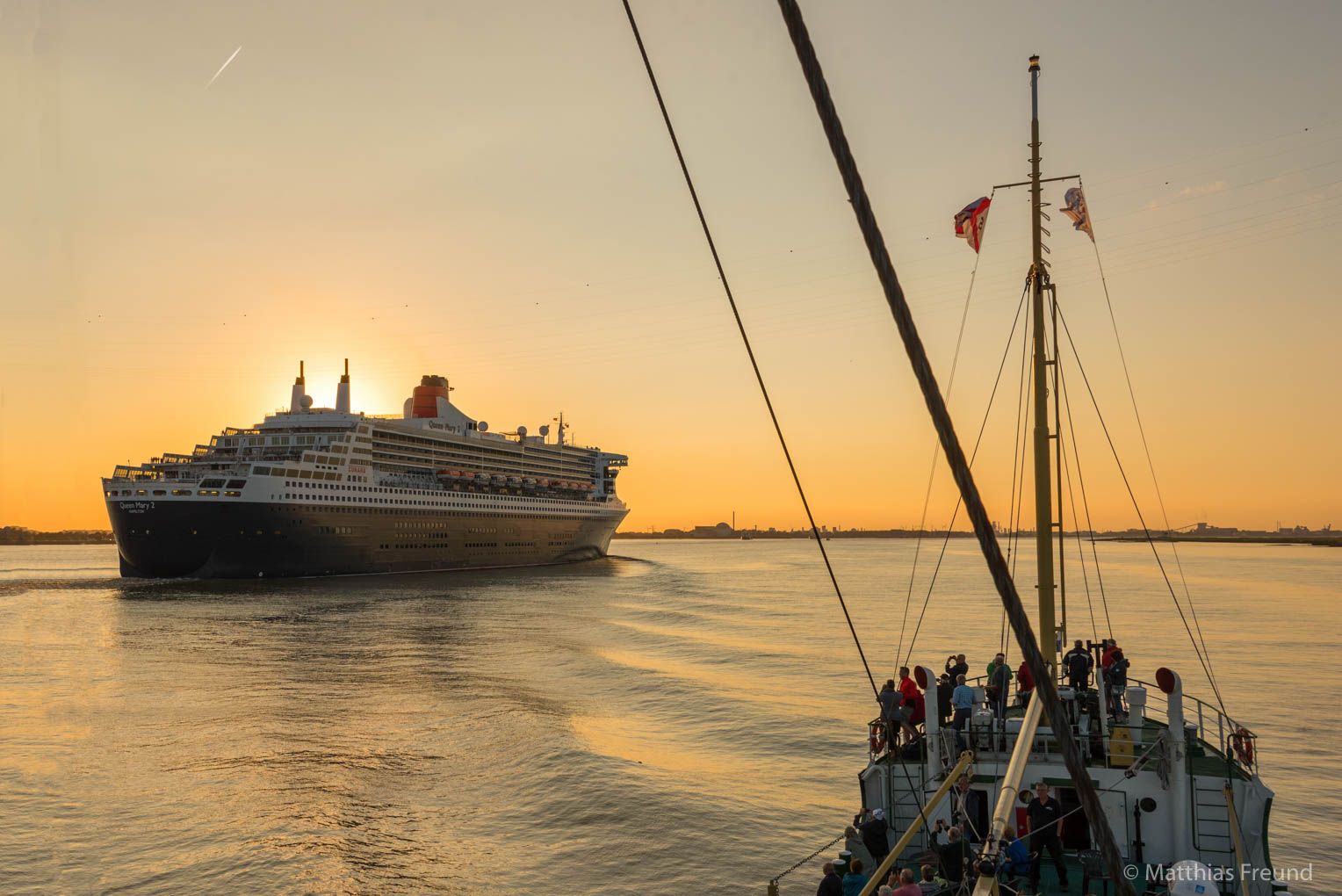 Abendstimmung auf der Elbe: Blick vom Deck der Greundiek auf die Queen Mary 2 vor der untergehenden Sonne